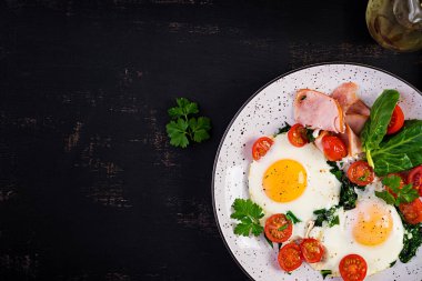 Keto diyet yemekli tabak. Yağda yumurta, jambon, ıspanak ve domates. Keto, paleo kahvaltısı. Üst görünüm, alanı kopyala