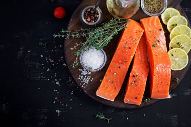 Çiğ somon fileto ve koyu bir arka planda pişirmek için malzemeler. Üst manzara, düz uzanma