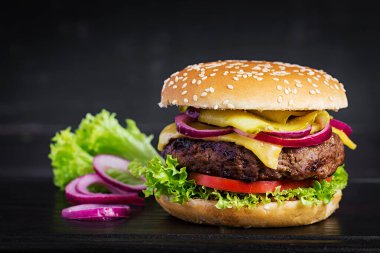 Büyük sandviç - hamburgerli biftek, domates, peynir, salatalık turşusu ve kırmızı soğanlı.