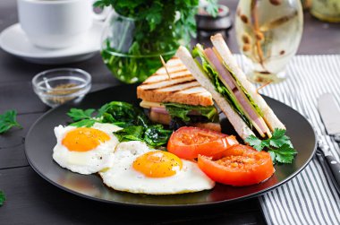 Kahvaltı: kızarmış yumurta, ıspanak, domates ve klüp sandviçi.