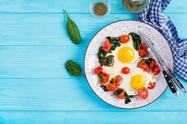 Kahvaltıda. Ketojenik diyet yiyecekler. Yağda yumurta, ıspanak ve domates. Keto, paleo kahvaltısı. Üst görünüm, alanı kopyala