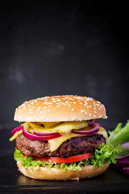 Büyük sandviç - hamburgerli biftek, domates, peynir, salatalık turşusu ve kırmızı soğanlı.