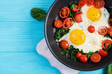 Kahvaltıda. Ketojenik diyet yiyecekler. Yağda yumurta, ıspanak ve domates. Keto, paleo kahvaltısı. Üst görünüm, alanı kopyala
