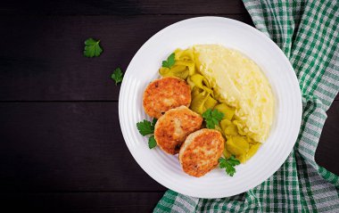 Ev yapımı pirzola, patates püresi ve beyaz tabakta salatalık turşusu ile köfte. Üst görünüm, genel görünüm, kopyalama alanı.