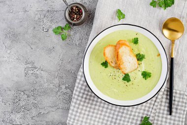 Ev yapımı brokoli kremalı çorba ve gri arka planda beyaz kâse. Sağlıklı vejetaryen yemekleri. Vejetaryen menüsü. Üst görünüm, alanı kopyala