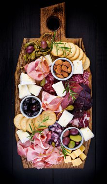 Ahşap zemin üzerinde jambon, jambon, jambon, salam, peynir, kraker ve zeytinli Antipasto tabağı. Noel masası. Üst görünüm, genel görünüm
