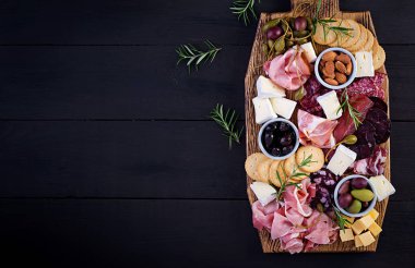Ahşap zemin üzerinde jambon, jambon, jambon, salam, peynir, kraker ve zeytinli Antipasto tabağı. Noel masası. Üst görünüm, genel görünüm