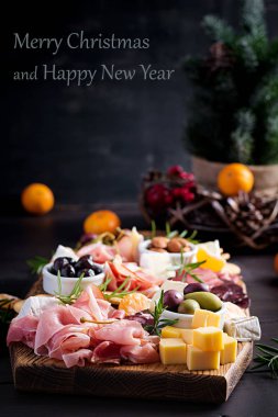 Ahşap zemin üzerinde jambon, jambon, jambon, salam, peynir, kraker ve zeytinli Antipasto tabağı. Noel masası.
