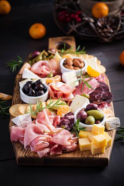 Ahşap zemin üzerinde jambon, jambon, jambon, salam, peynir, kraker ve zeytinli Antipasto tabağı. Noel masası.