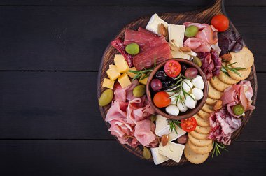 Ahşap zemin üzerinde jambon, jambon, jambon, salam, peynir, kraker ve zeytinli Antipasto tabağı. Noel masası. Üst görünüm, genel görünüm