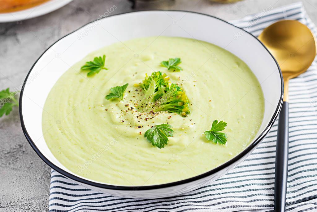 Homemade broccoli cream soup with croutons in white bowl on grey background. Healthy vegetarian food. Vegan menu.