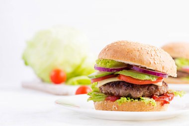 Büyük sandviç - sığır etli hamburger, avokado, domates ve açık arkaplanda kırmızı soğan. Amerikan mutfağı. Fast Food