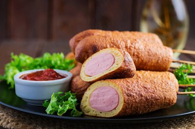 Siyah tabakta hardallı ve ketçaplı geleneksel Amerikan mısırlı sosisleri. Sokak yemeği. Boşluğu kopyala