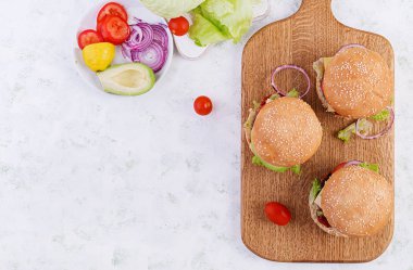 Büyük sandviç - sığır etli hamburger, avokado, domates ve açık arkaplanda kırmızı soğan. Amerikan mutfağı. Fast Food. Üst görünüm, genel görünüm