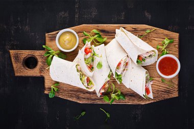 Tavuklu taze tortilla ve tahta tahtada taze sebzeler. Tavuk dürüm. Meksika yemeği. Sağlıklı gıda konsepti. Meksika mutfağı. Üst manzara, genel giderler.