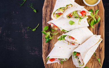 Tavuklu taze tortilla ve tahta tahtada taze sebzeler. Tavuk dürüm. Meksika yemeği. Sağlıklı gıda konsepti. Meksika mutfağı. Üst manzara, genel giderler.