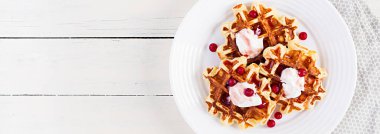 Geleneksel Belçika waffleları böğürtlenli, ekşi kremalı ve reçelli beyaz ahşap masa. Üst görünüm, afiş