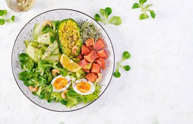 Ketogenik diyet kahvaltısı. Sebzeli tuzlu somon salatası, salatalık, yumurta ve avokado. Keto / Paleo öğle yemeği. Üst görünüm, genel görünüm