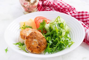 Ketogenik öğle yemeği. Domatesli tavuk burger, salatalık, peynir ve ekmeksiz roka salatası. Tavuk köftesi. Sağlıklı yiyecekler. Keto / paleo diyeti.