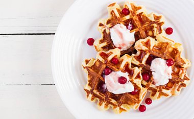 Geleneksel Belçika waffleları böğürtlenli, ekşi kremalı ve reçelli beyaz ahşap masa. Üst görünüm, genel görünüm