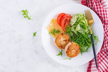 Ketogenik öğle yemeği. Domatesli tavuk burger, salatalık, peynir ve ekmeksiz roka salatası. Tavuk köftesi. Sağlıklı yiyecekler. Keto / paleo diyeti. Üst görünüm, genel görünüm