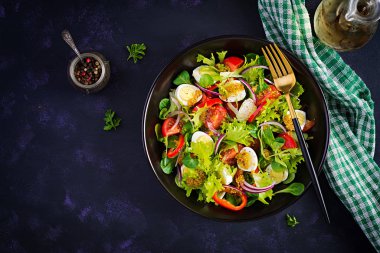 Sebzeli taze salata, domates, kırmızı soğan, marul ve bıldırcın yumurtası. Sağlıklı gıda ve diyet konsepti. Vejetaryen yemeği. Üst görünüm, genel görünüm
