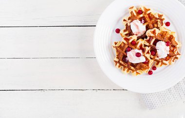 Geleneksel Belçika waffleları böğürtlenli, ekşi kremalı ve reçelli beyaz ahşap masa. Üst görünüm, genel görünüm
