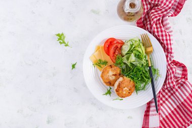 Ketogenik öğle yemeği. Domatesli tavuk burger, salatalık, peynir ve ekmeksiz roka salatası. Tavuk köftesi. Sağlıklı yiyecekler. Keto / paleo diyeti. Üst görünüm, genel görünüm