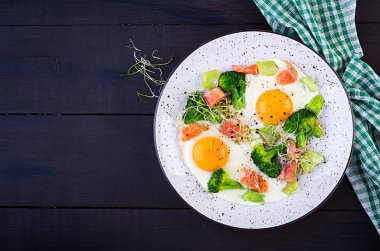 Ketogenik / paleo diyeti. Kızarmış yumurta, somon, brokoli ve mikroyeşil. Keto kahvaltısı. Brunch olsun. Üst görünüm, genel görünüm