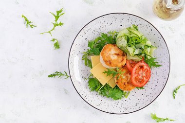 Ketogenik öğle yemeği. Domatesli tavuk burger, salatalık, peynir ve ekmeksiz roka salatası. Tavuk köftesi. Sağlıklı yiyecekler. Keto / paleo diyeti. Üst görünüm, genel görünüm