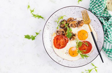 Ketojenik gıda. Yağda yumurta, mantar ve dilimlenmiş domates. Keto, paleo kahvaltısı. Üst görünüm, genel görünüm, kopyalama alanı