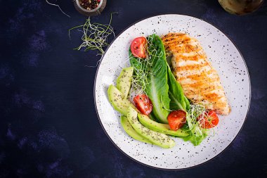 Salata, taze domates ve avokado ile ızgara tavuk filetosu. Sağlıklı yiyecekler, ketojenik diyet, diyet öğle yemeği konsepti. Keto / Paleo diyet menüsü. Üst manzara, düz uzanma
