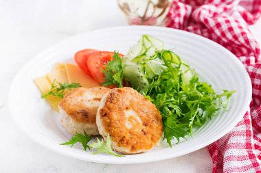 Ketogenik öğle yemeği. Domatesli tavuk burger, salatalık, peynir ve ekmeksiz roka salatası. Tavuk köftesi. Sağlıklı yiyecekler. Keto / paleo diyeti.