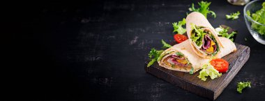 Jambonlu taze tortilla sargıları ve tahta tahtada taze sebzeler. Biftek dürümü. Meksika mutfağı. Pankart