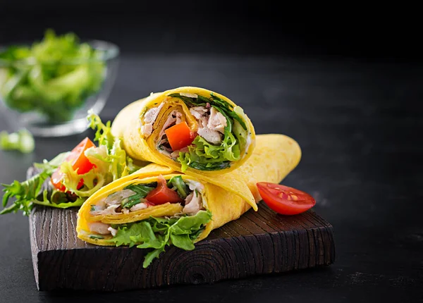Fresh tortilla wraps with chicken and fresh vegetables on wooden board. Chicken burrito. Mexican cuisine. Copy space