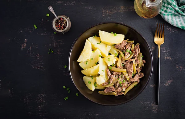 Fígado frito com cebola, batata doce e salada no prato branco