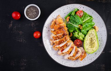 Moda salatası. Salata, taze domates ve avokado ile ızgara tavuk filetosu. Sağlıklı yiyecekler, ketojenik diyet, diyet öğle yemeği konsepti. Keto / Paleo diyet menüsü. Üst görünüm, genel görünüm, düz görünüm