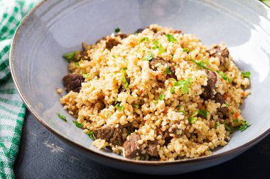 Et ve sebzeli Bulgur pilavı. Siyah arka planda lezzetli, sağlıklı bir öğle yemeği. Doğu mutfağı.