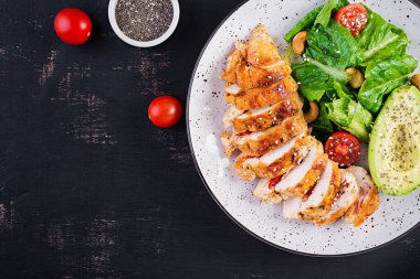 Moda salatası. Salata, taze domates ve avokado ile ızgara tavuk filetosu. Sağlıklı yiyecekler, ketojenik diyet, diyet öğle yemeği konsepti. Keto / Paleo diyet menüsü. Üst görünüm, genel görünüm, düz görünüm