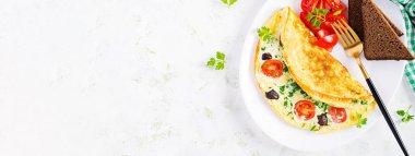 Kahvaltıda. Domatesli omlet, siyah zeytin, süzme peynir ve beyaz tabakta yeşil otlar. Frittata - İtalyan omleti. Üst görünüm, afiş