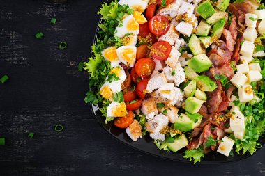 Tavuk, avokado, pastırma, domates, peynir ve yumurtalı sağlıklı Cobb salatası. Amerikan yemeği. Üst Manzara. Düz uzanın, başınızın üstünde