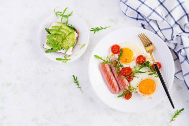 İngiliz kahvaltısı - sahanda yumurta, sosis, domates ve roka. Amerikan yemeği. Üst görünüm, genel görünüm, kopyalama alanı