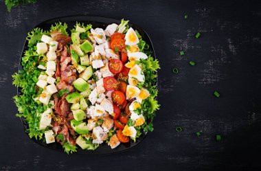 Tavuk, avokado, pastırma, domates, peynir ve yumurtalı sağlıklı Cobb salatası. Amerikan yemeği. Üst Manzara. Düz uzanın, başınızın üstünde