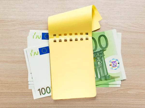 Cent billets en euros et bloc-notes jaune — Photo