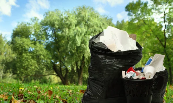 Voller schwarzer Papierkorb und Plastiktüten — Stockfoto