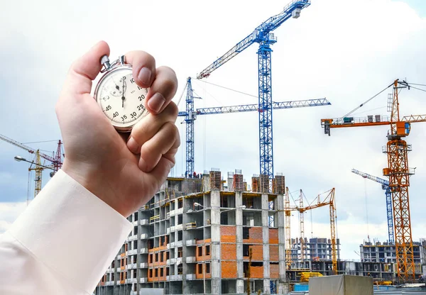 Gebäude mit Kränen und Stoppuhr in Männerhand — Stockfoto