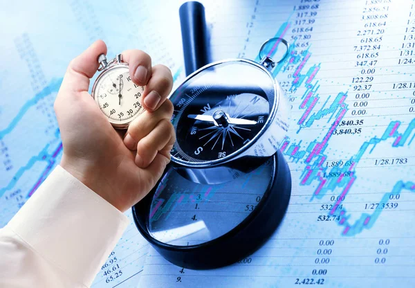 Kompas, uitvergroten glas, candlestick grafiek en stopwatch in de hand — Stockfoto