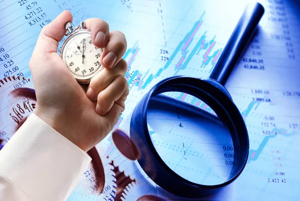 Budget, magnifying glass, candlestick chart and stopwatch in hand — Stock Photo, Image