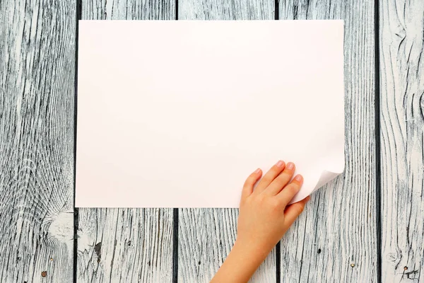 Child's hand turning over paper — Stock Photo, Image