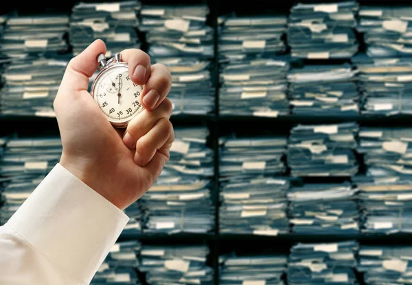 Paper documents stacked archive and stopwatch in hand — Stock Photo, Image